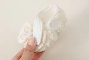 Detail of cream baby princess shoe showing lace flower texture and velcro strap