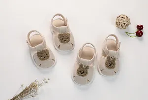 Close-up of baby sandals with cute plush bear and rabbit patches on breathable fabric