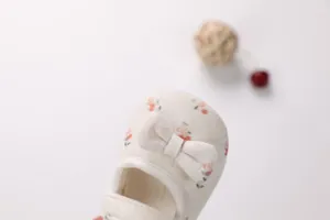 Dettaglio di scarpe da principessa per neonati con motivo a ciliegie e fiocco decorativo