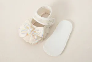 Close-up of baby princess shoe with lace detail, ribbon bow, and decorative pearls
