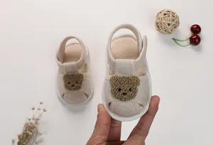 Detail of baby summer sandals featuring a cute brown bear patch and velcro strap
