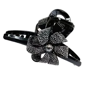 Grande pince à cheveux 13cm en résine noire avec nœud en strass sur fond blanc épuré