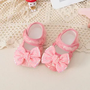Pink lace baby girl Mary Jane shoes with large rhinestone bow on a white lace background