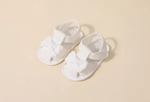 Vue détaillée de sandales blanches pour bébés avec nœud décoratif et bande velcro