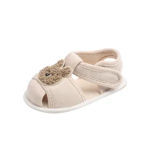 Detail showing plush bear motif and breathable cotton upper on beige baby summer sandals