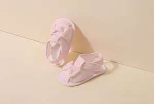 Gros plan de sandales roses pour bébés avec dentelle, nœud et fermeture velcro