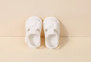 Détail de sandales bébé en dentelle de coton blanche avec broderie et nœud décoratif