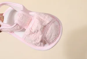 Gros plan détaillé de sandale rose bébé avec broderie florale et nœud papillon