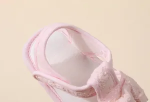 Détail de la texture en dentelle rose et de la bande velcro sur les sandales bébé