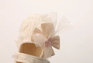 Detail von weißen Baby-Prinzessinenschuhen aus Spitze mit Schleife und handgefertigter Blume
