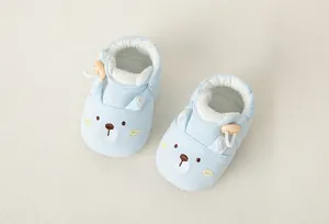 Detail von hellblauem Baby-Lauflernschuh mit gesticktem Bären und Holzknopf-Verschluss