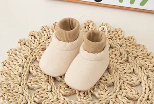 Detail of baby sock shoes featuring rib knit cuffs and anti-slip soft soles in beige