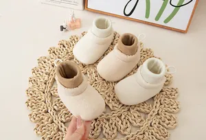 Detailed view of cream and khaki baby sock shoes with ribbed cuffs on a cozy mat