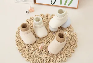 Close-up of soft knit baby walking shoes on a woven mat with warm decorative background