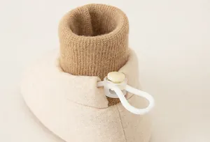 Detailed close-up of brown ribbed knit cuff and adjustable toggle on baby walking shoes