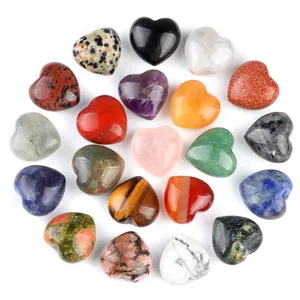 Polished natural crystal heart stones in various colors arranged on white background