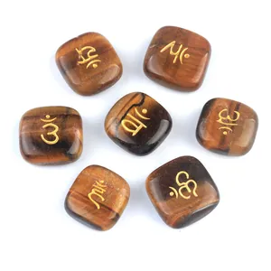 Set of seven square tiger eye chakra stones with golden engraved symbols on white background