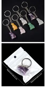 Macro detail of hand-carved gemstone owl keychains with silver rings on black background