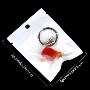 Carved dolphin keychain made of orange agate stone in packaging measuring 8cm by 6cm