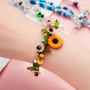 Dettaglio del bracciale fatto a mano con girasole e margherite indossato sul polso