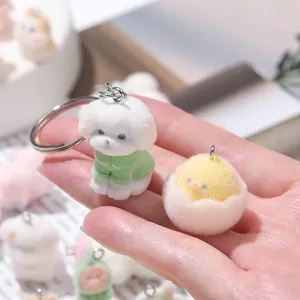 Close-up of cute flocked animal charms including a white puppy and a yellow chick in hand