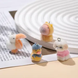 Close-up of four flocked animal pendants including a capybara and duck on a white tray