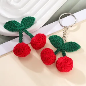 Handmade crochet cherry keychain charm with red yarn fruits and green leaves on a white base