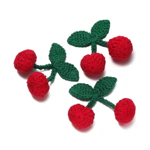 Detailed close-up of handmade crochet red cherries and green leaves for DIY crafts