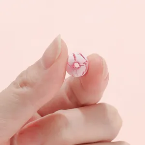 Macro detail of 8mm pink acrylic crackle bead with deep red texture for DIY jewelry