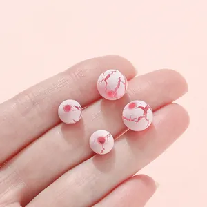 Pink crackle acrylic beads for DIY jewelry making shown in hand for size reference