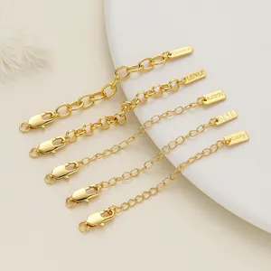 Close-up of assorted 18K gold-plated jewelry extension chains with engraved logo tags