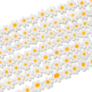 Macro shot of white daisy glass beads with yellow centers for DIY jewelry making