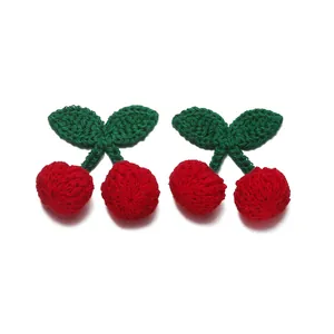 Detailed view of handmade crochet cherry charms showing soft knitted texture and stitching