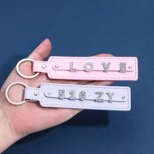 Dettaglio di portachiavi in pelle fai-da-te con lettere e numeri di strass rosa e viola