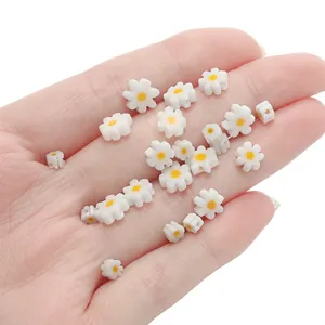 White glass daisy beads with yellow center for DIY jewelry making held in palm