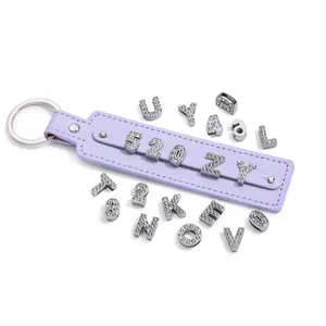 Dettaglio del portachiavi DIY con cinturino in pelle viola e lettere in strass argento