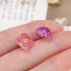 Macro view of translucent glass flower charms in pink and purple with gold centers