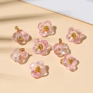 Detail of eight transparent pink glass flower pendants with gold bead accents for DIY jewelry