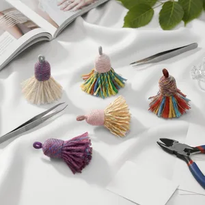 Flat lay of colorful handmade cotton tassels with DIY jewelry making tools on white fabric