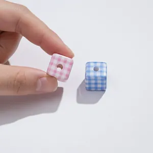 Detail of pink acrylic gingham cube bead with central hole for DIY jewelry making