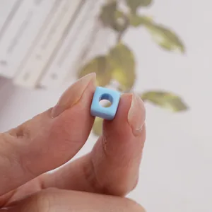 Detailed close-up of 7mm light blue square bead with hole for DIY jewelry making