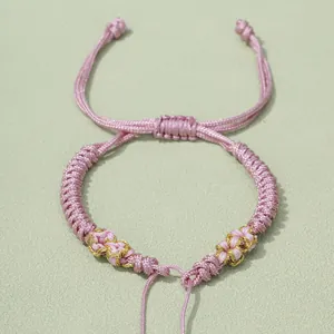 Detailaufnahme von handgewebtem Armband in Pink und Gold mit verstellbarem Schiebeknoten