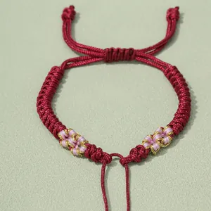 Detail von handgeflochtenem bordeauxrotem Armband mit rosa Zierknoten-Muster