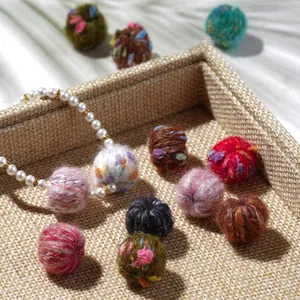 Close-up of colorful wool felt pompom balls for DIY jewelry making in a woven tray