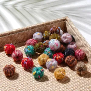 Close-up of colorful handmade plush pom-poms with soft wool fiber texture on a tray