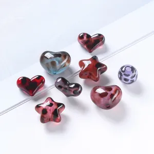 Dettaglio macro di perle acriliche leopardate a forma di cuore, stella e sfera