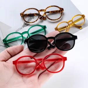 Close-up of miniature round doll glasses in multiple colors held by hand for scale