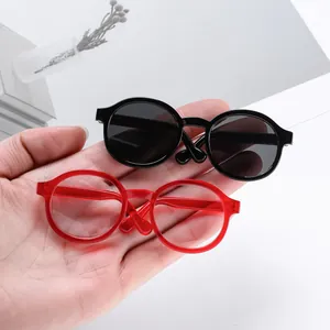 Miniature round-frame doll glasses set in black and transparent red colors held by hand