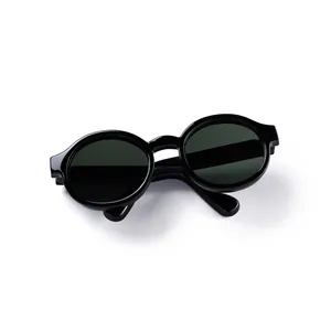 Detail of round retro doll sunglasses with high-polish black frames and dark lenses