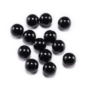 Perle in ABS nero lucido sparse su sfondo bianco per la creazione di gioielli fai-da-te